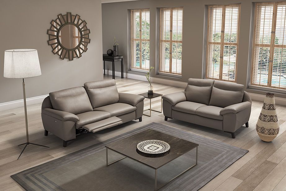 Soggiorno con divani grigi, tavolino da caffè, tappeto, ampie finestre.