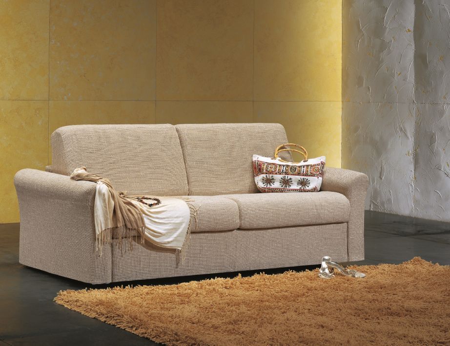 Divano beige con coperta, borsa e tappeto, in contrasto con pareti gialle e bianche.