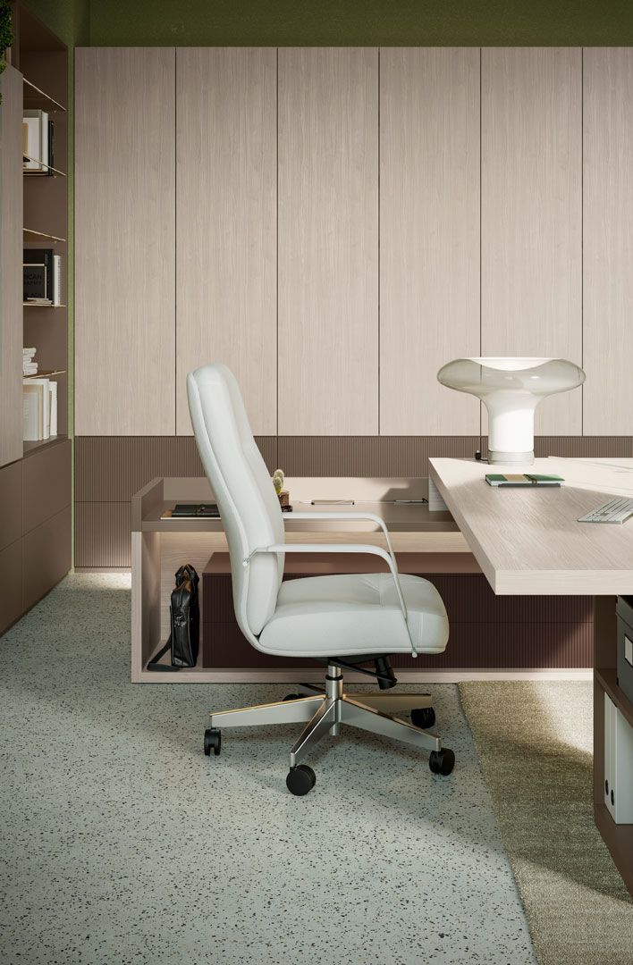 Interno di un ufficio con sedia in pelle grigio chiaro, scrivania e pannelli in legno. Pavimento in terrazzo.