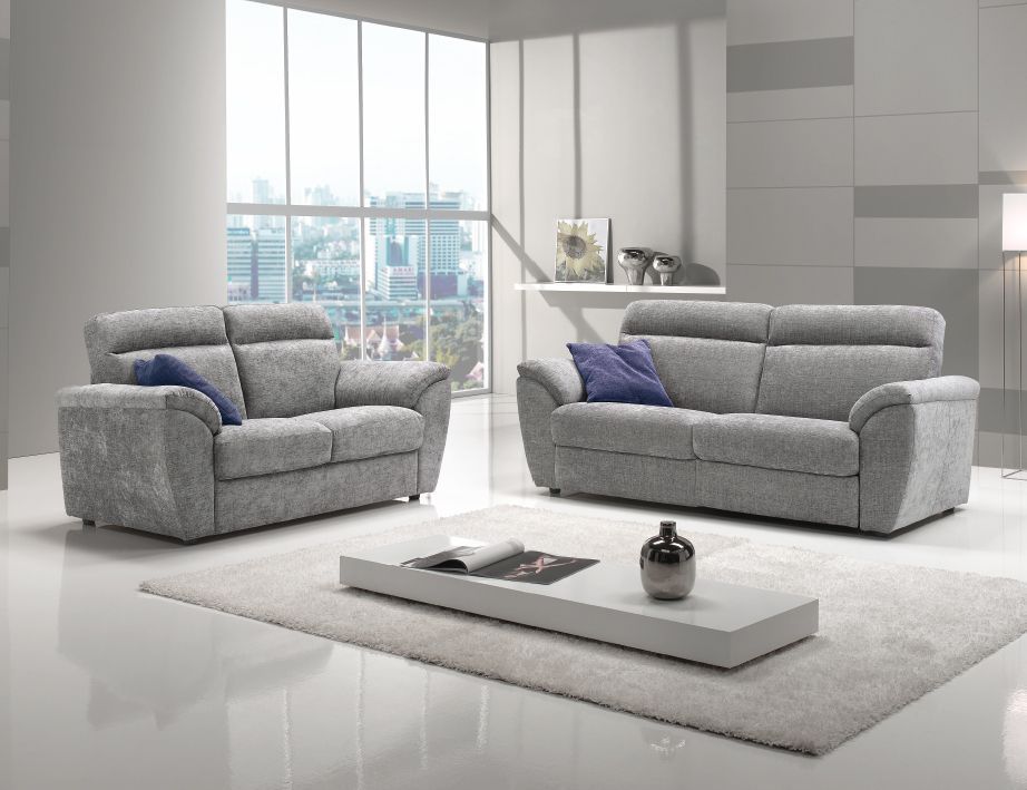 Soggiorno con divano grigio, divanetto, tavolino bianco e soffice tappeto. Ampie finestre garantiscono una luce intensa.