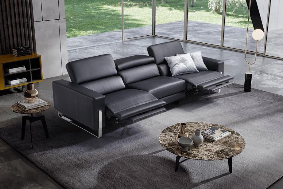 Divano reclinabile moderno in pelle nera nel soggiorno con tappeto e tavolino.