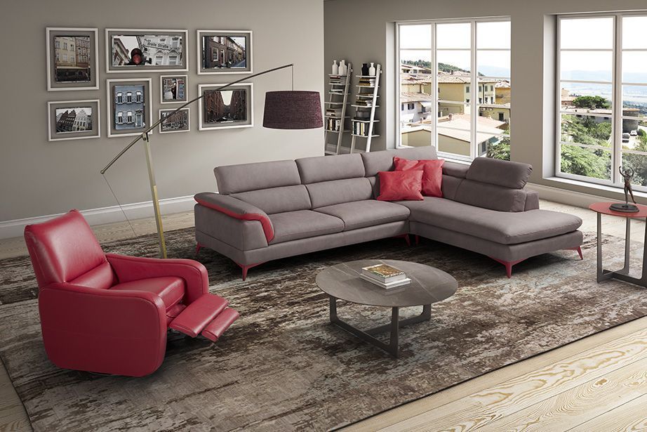 Soggiorno con divano componibile grigio, poltrona reclinabile rossa, tavolino da caffè e vista panoramica.