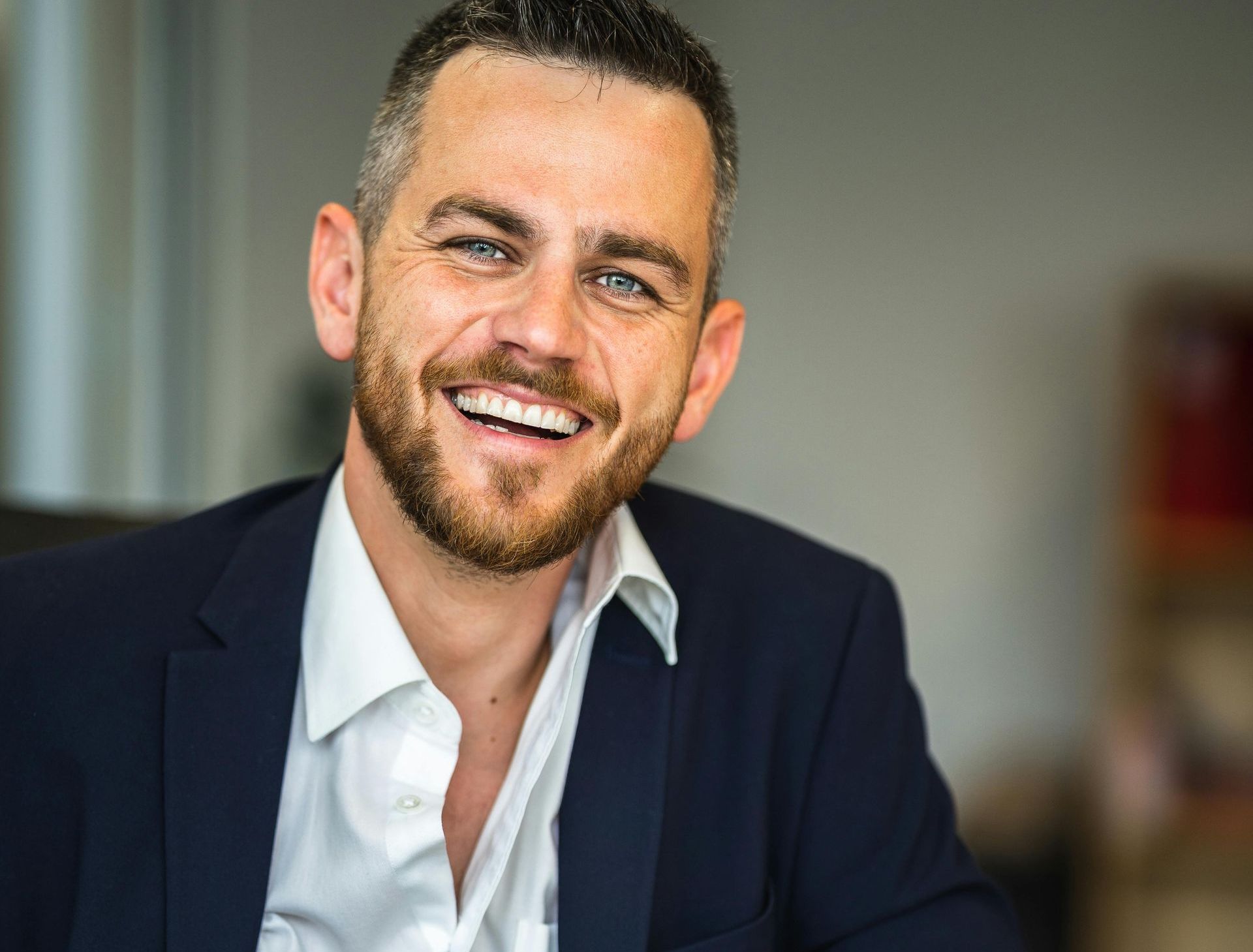 A man in a suit and white shirt is smiling for the camera.