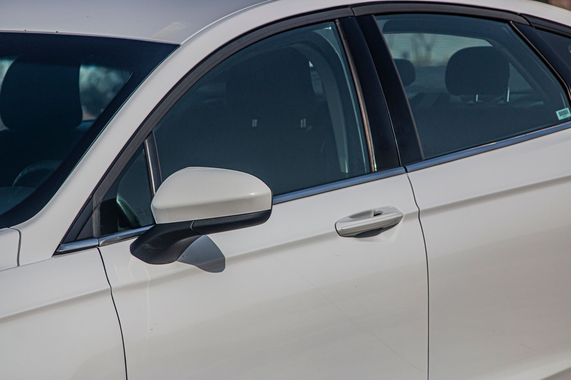 White car's side with the door and side mirror visible, parked outside.