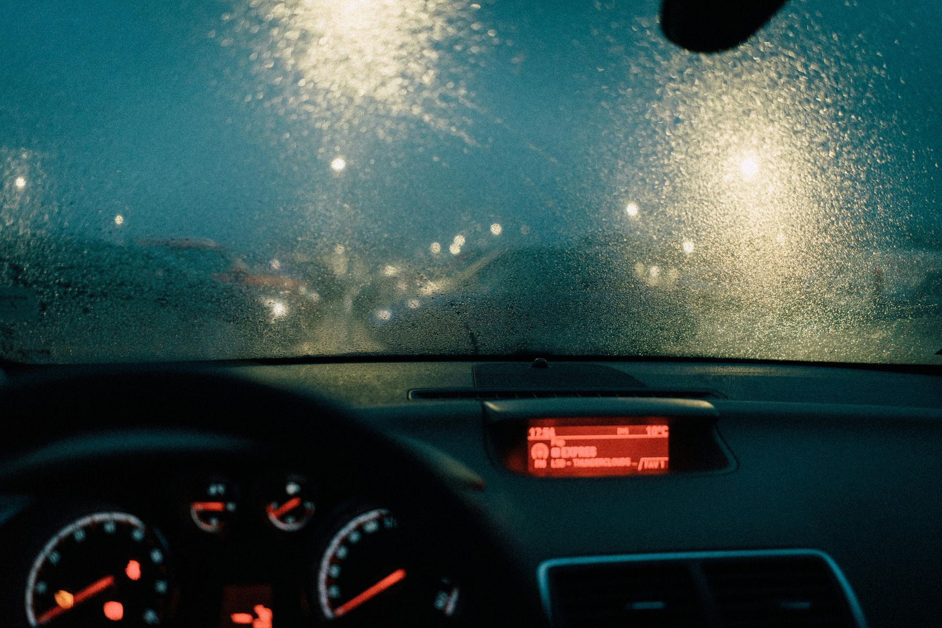 Interior car view, driving in heavy rain at night; dashboard visible.