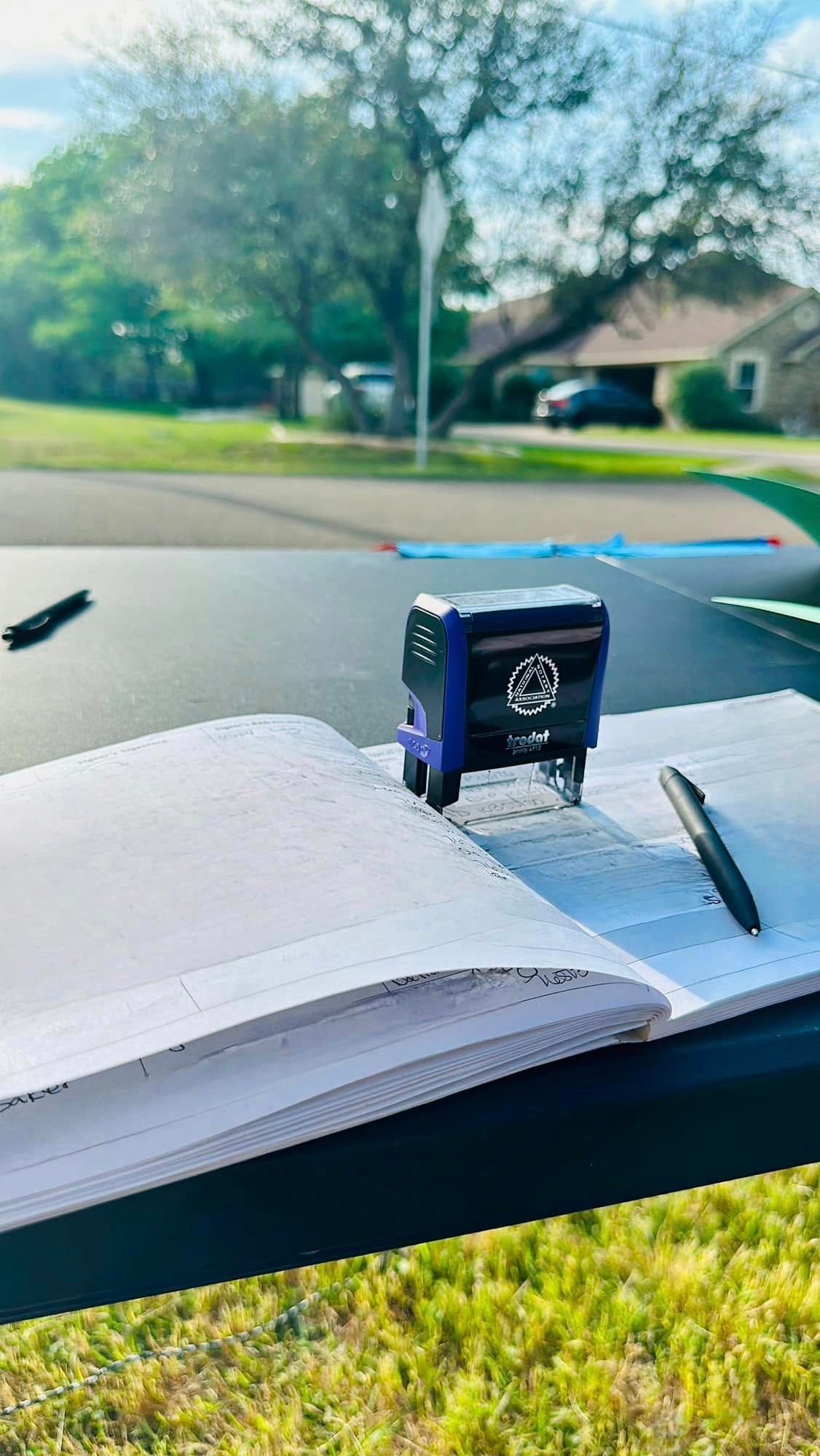 A purple stamp is sitting on top of a notebook with a pen.