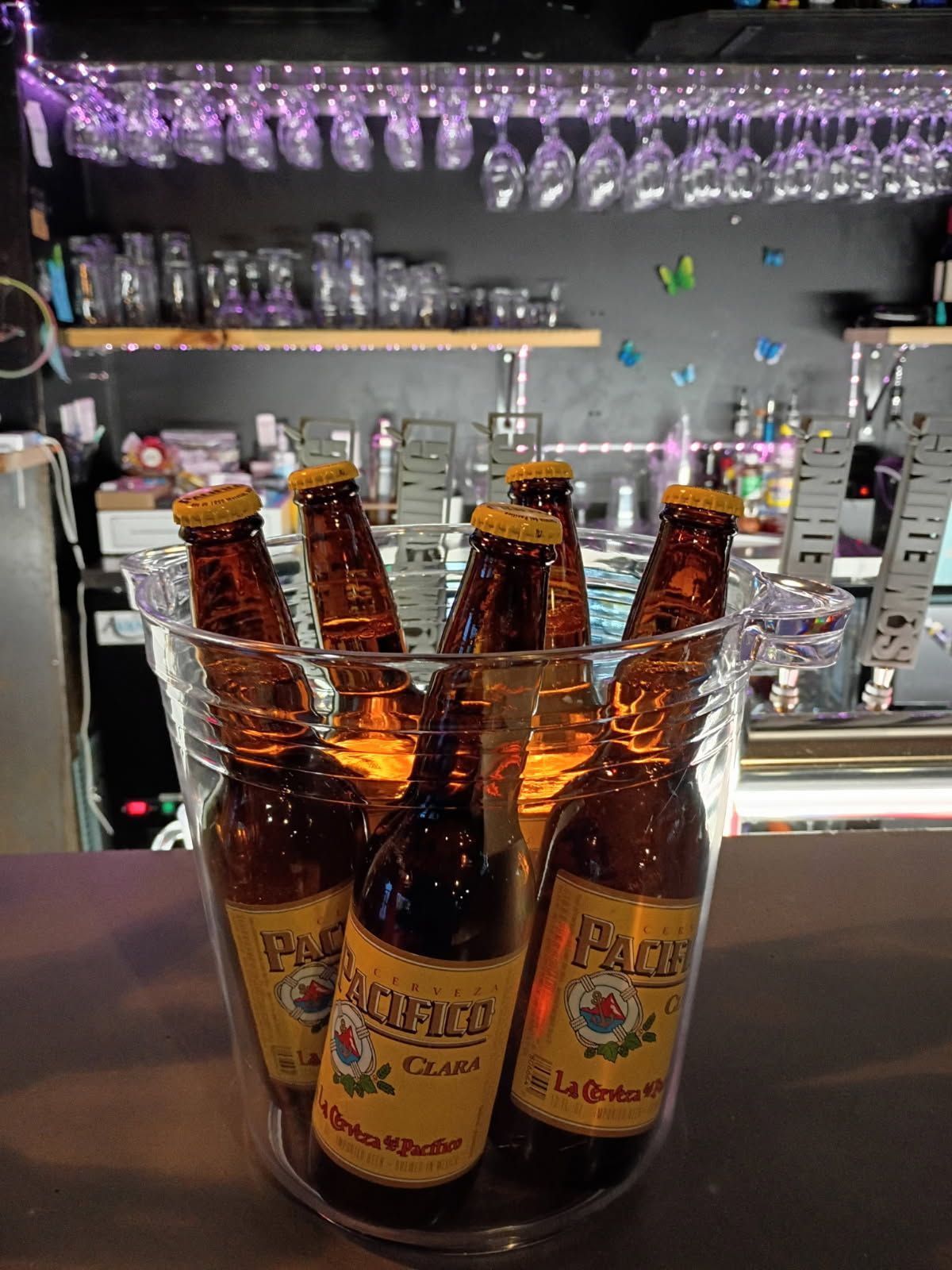 Close-up of shiny silver beer taps in a dimly lit bar, with colorful neon lighting.