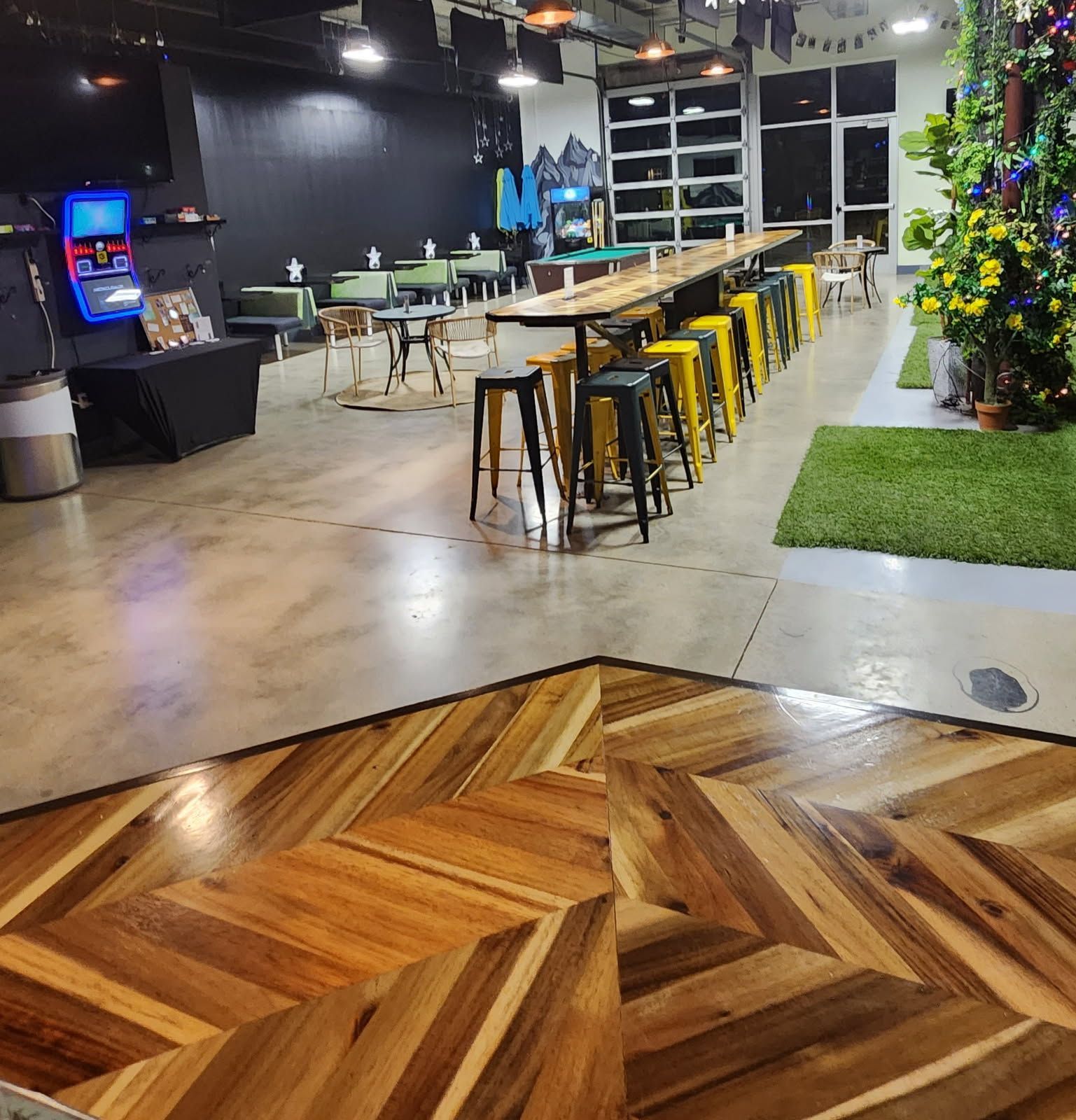 Wooden parquet floor leading to a room with tables, stools, and a Christmas tree.
