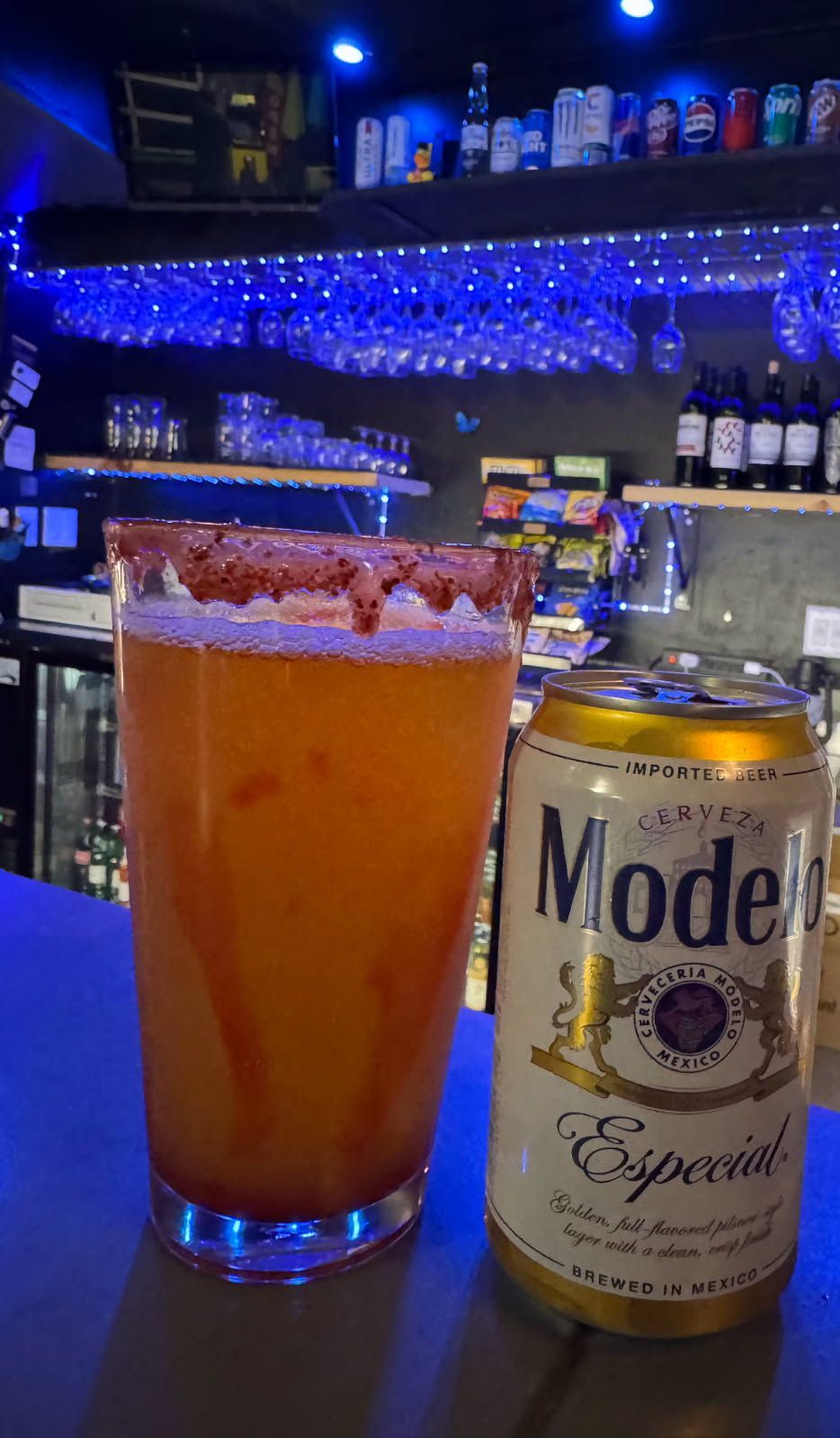 Glass beer mug, filled with golden beer, against a dark, bokeh background with blue and yellow lights.