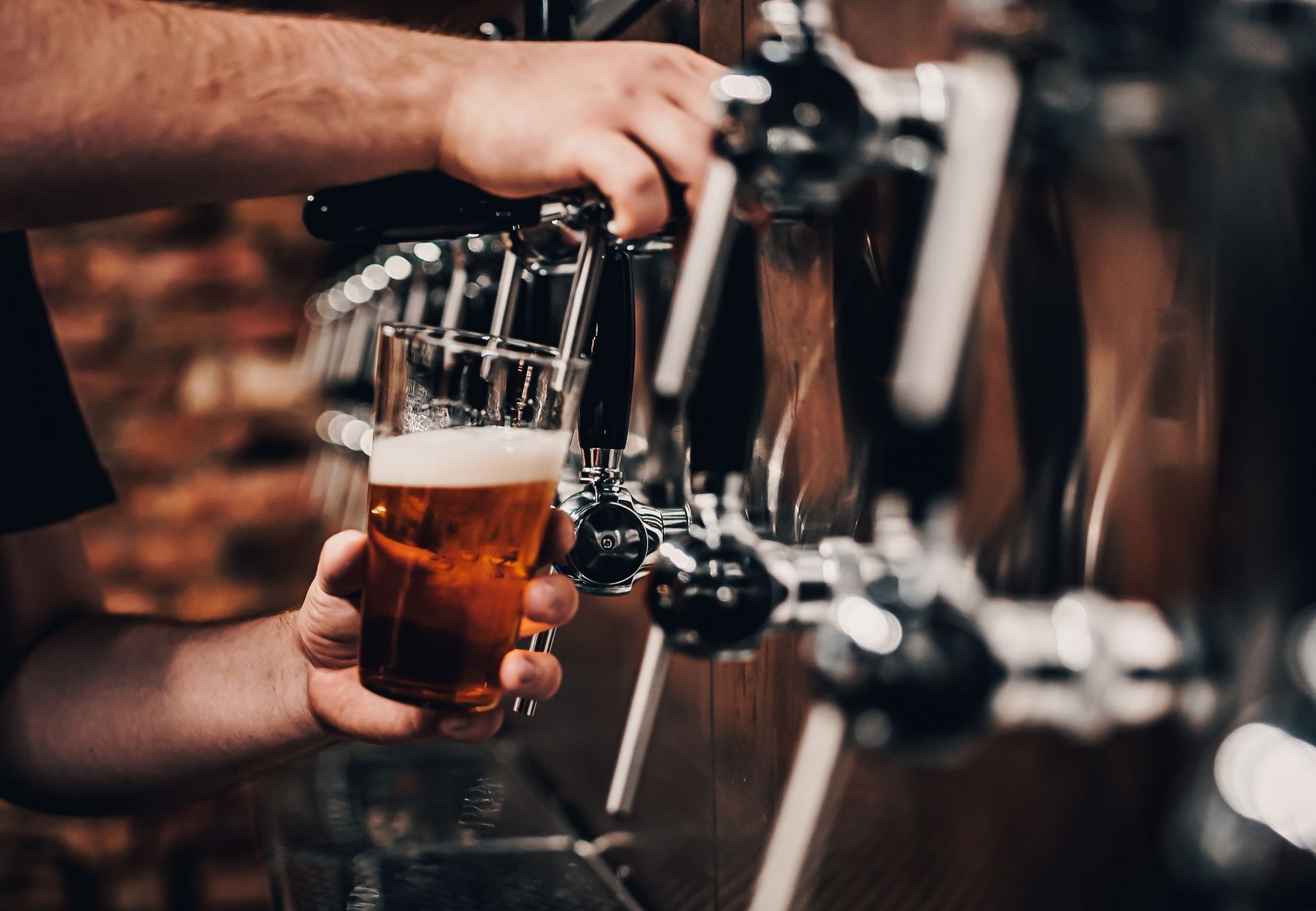 Bartender pouring beer from a tap into a glass at a bar.