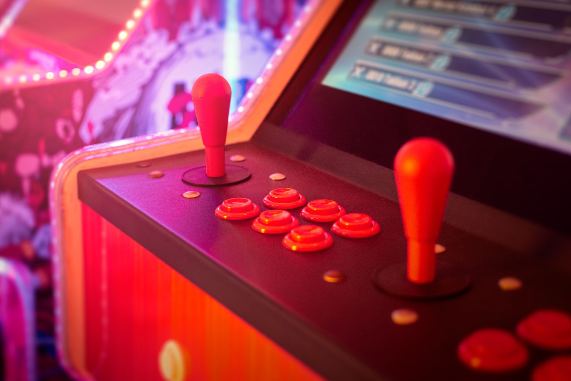 Arcade machine with red joysticks and buttons, illuminated in pink and orange.
