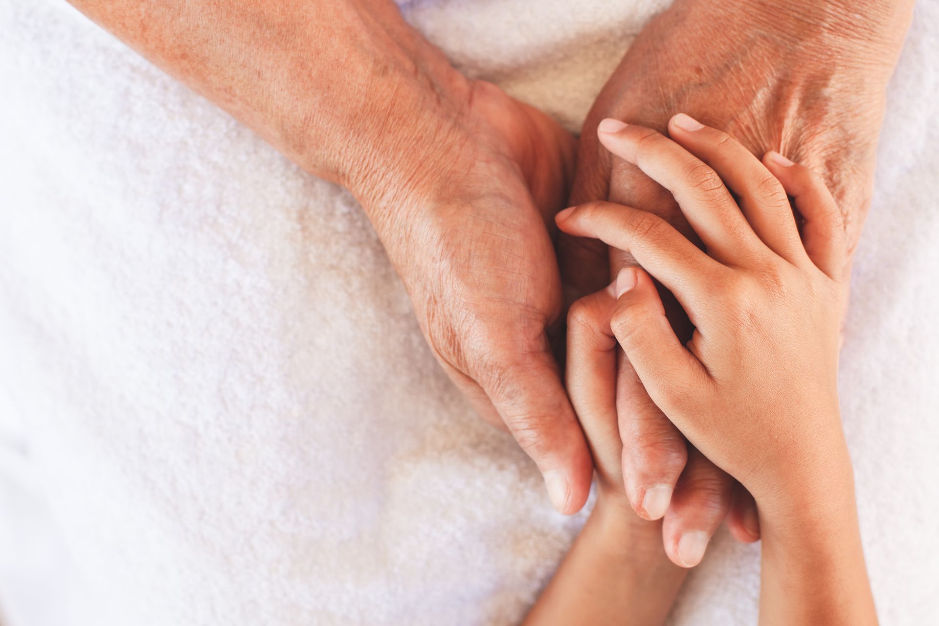 A man and a child are holding hands on a white towel.