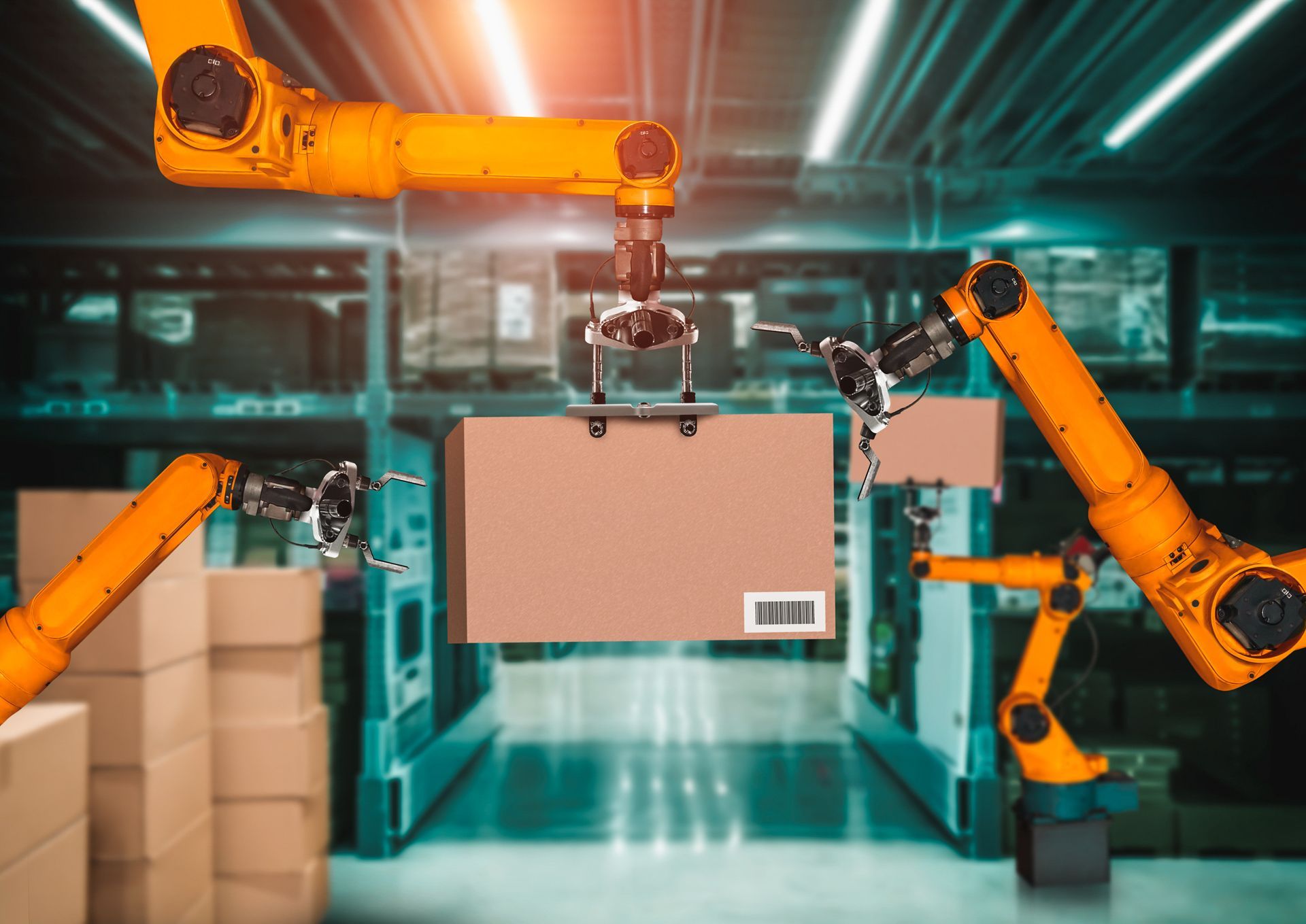 A group of robotic arms are lifting a cardboard box in a warehouse.