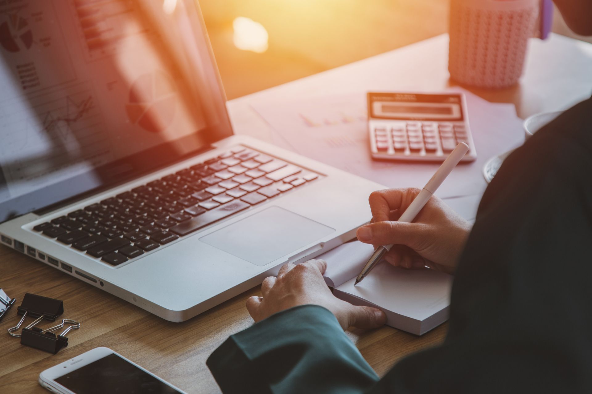 A person is sitting at a desk with a laptop and a calculator.