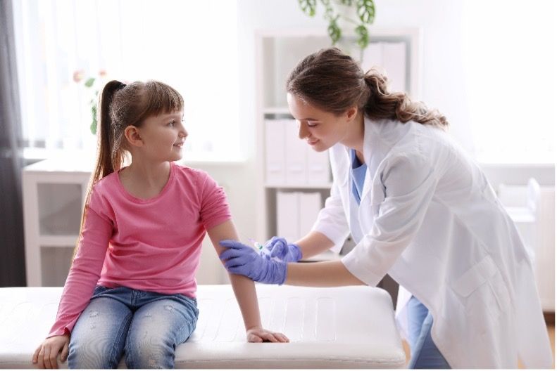 A doctor wearing purple nitrile gloves is giving a child an injection in her arm.