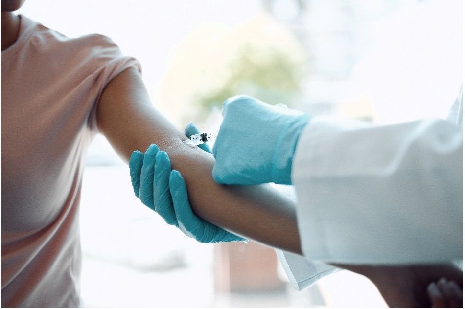 A doctor wearing latex gloves is giving a patient an injection in their arm.