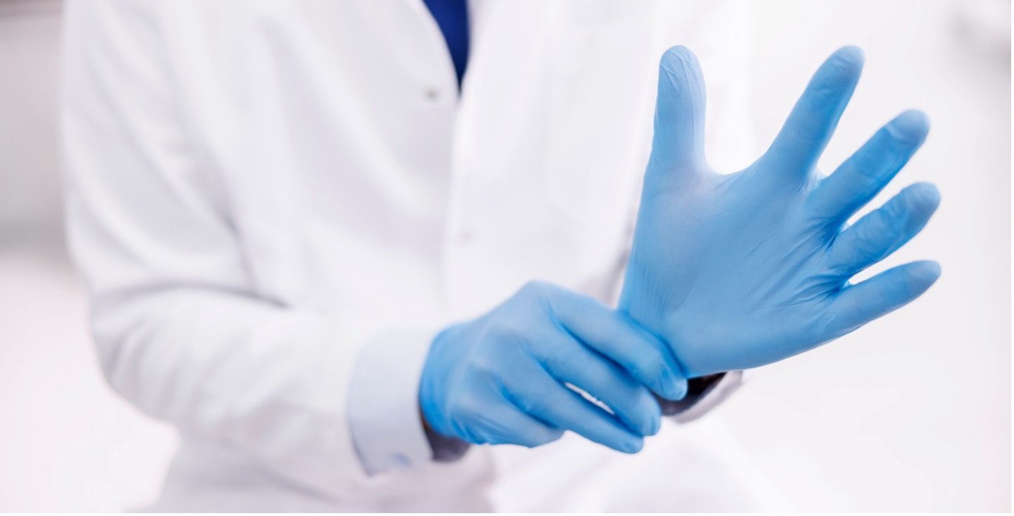 A person is putting on a pair of blue nitrile gloves.