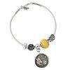 A silver charm bracelet featuring a yellow beaded charm and a round, dark metallic pendant with a floral design.