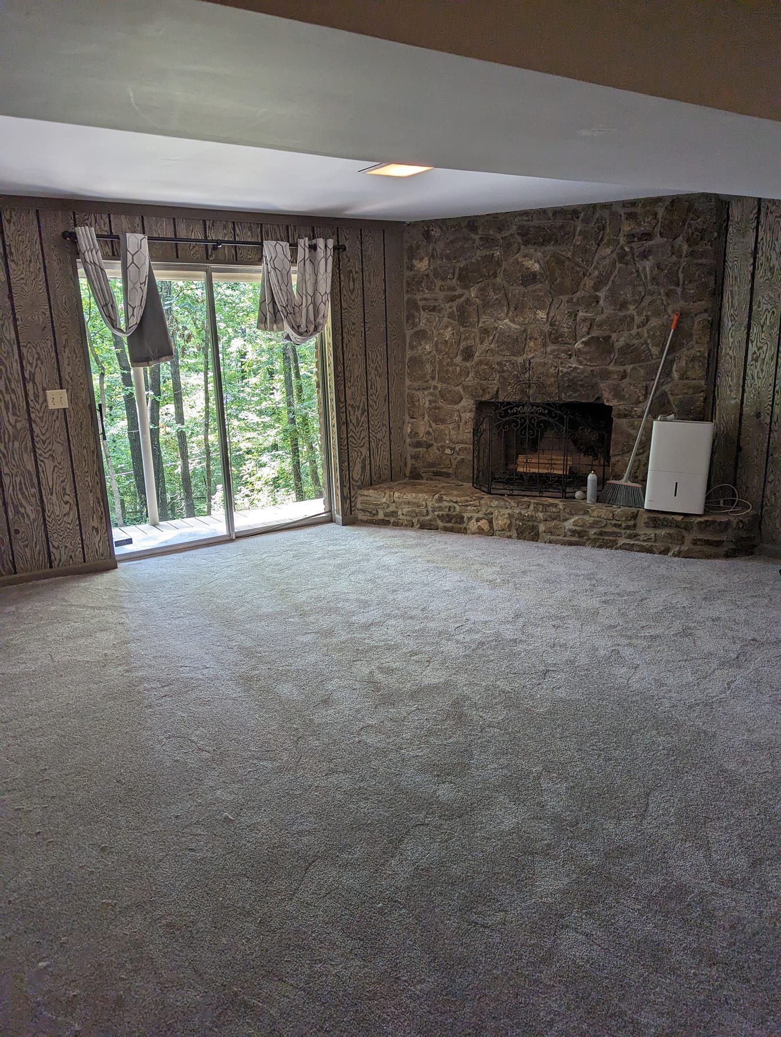 An empty living room with a fireplace and sliding glass doors.