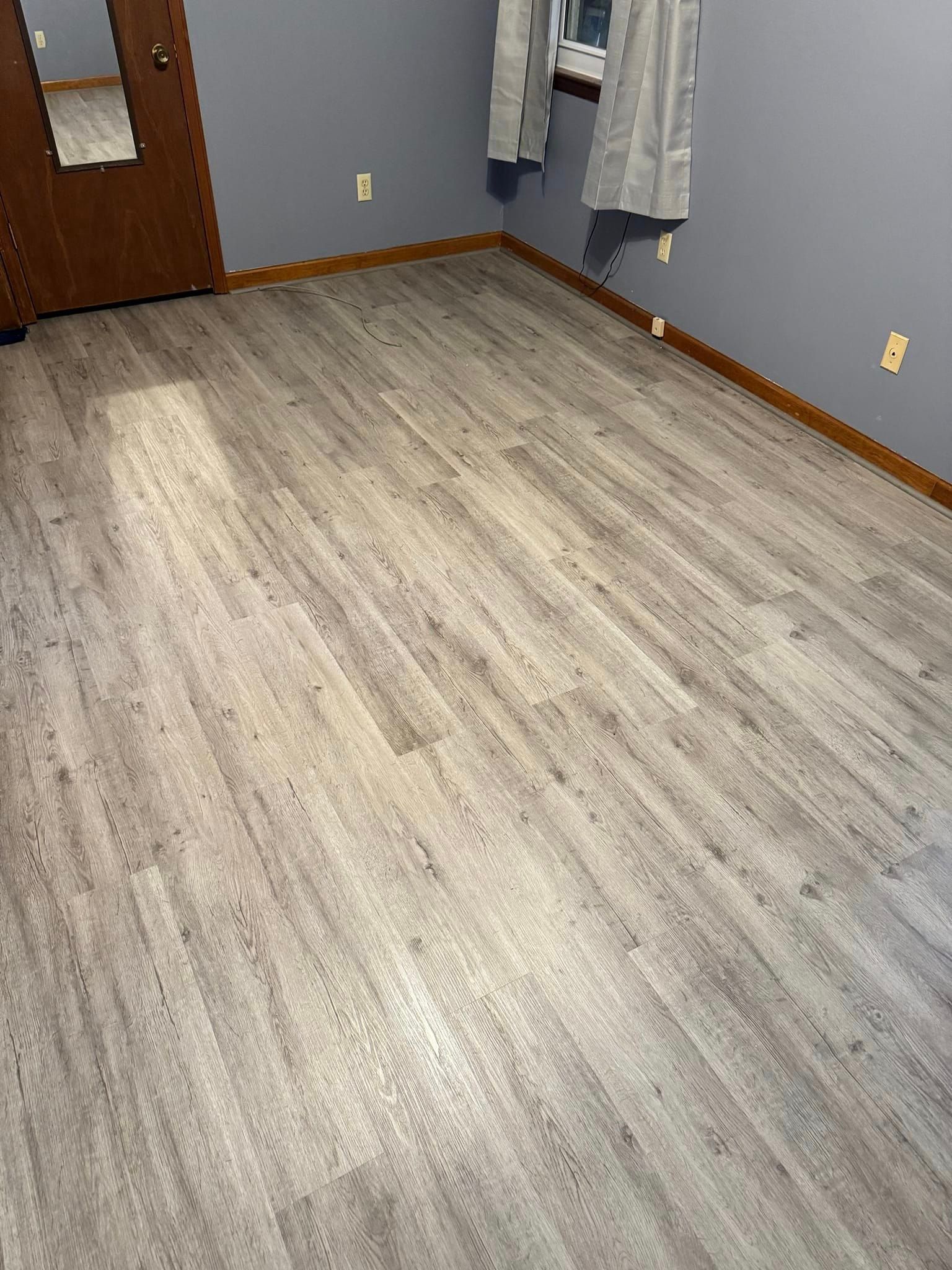 A bedroom with a wooden floor and a window.