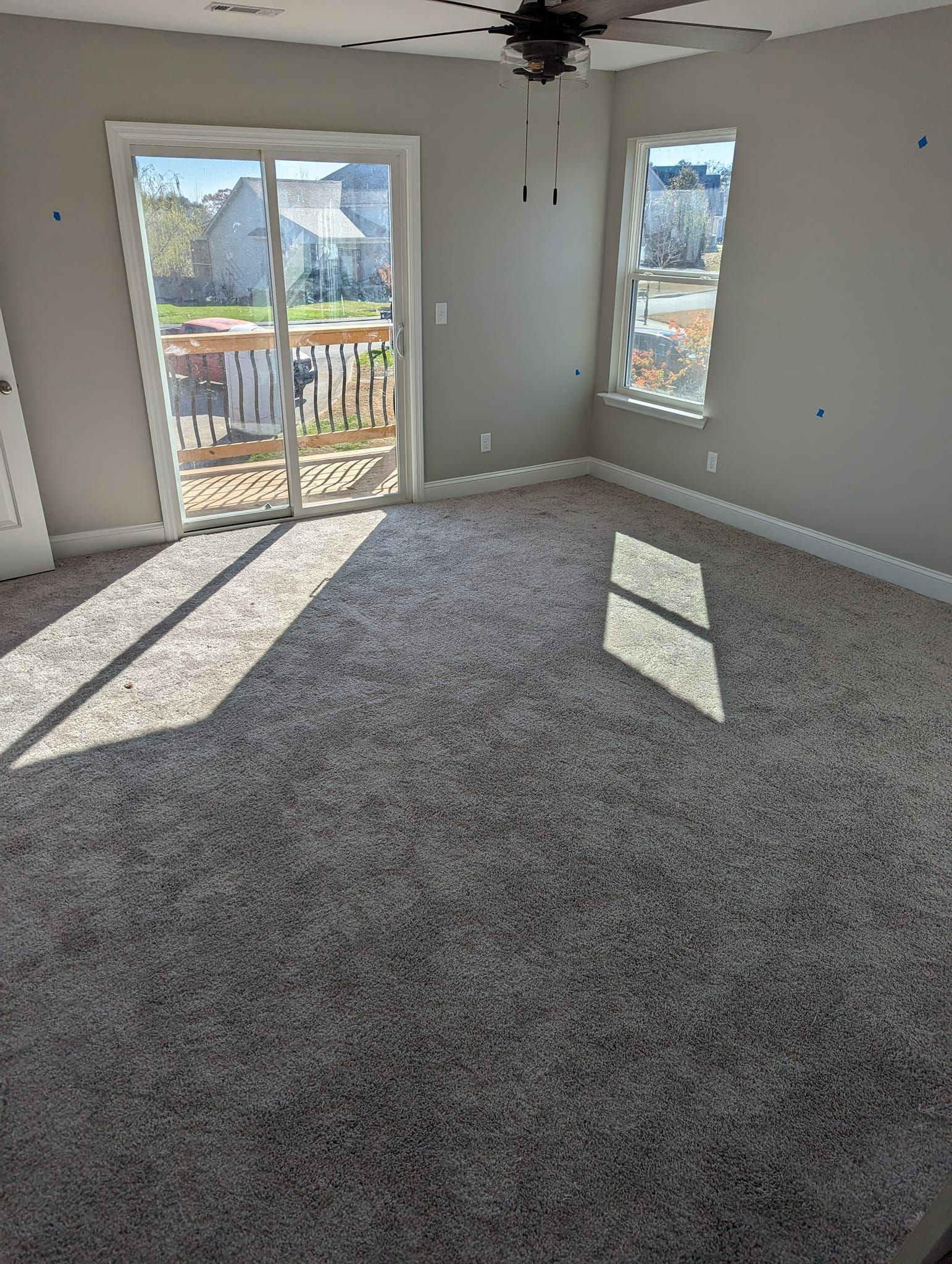 An empty room with a sliding glass door and a ceiling fan.