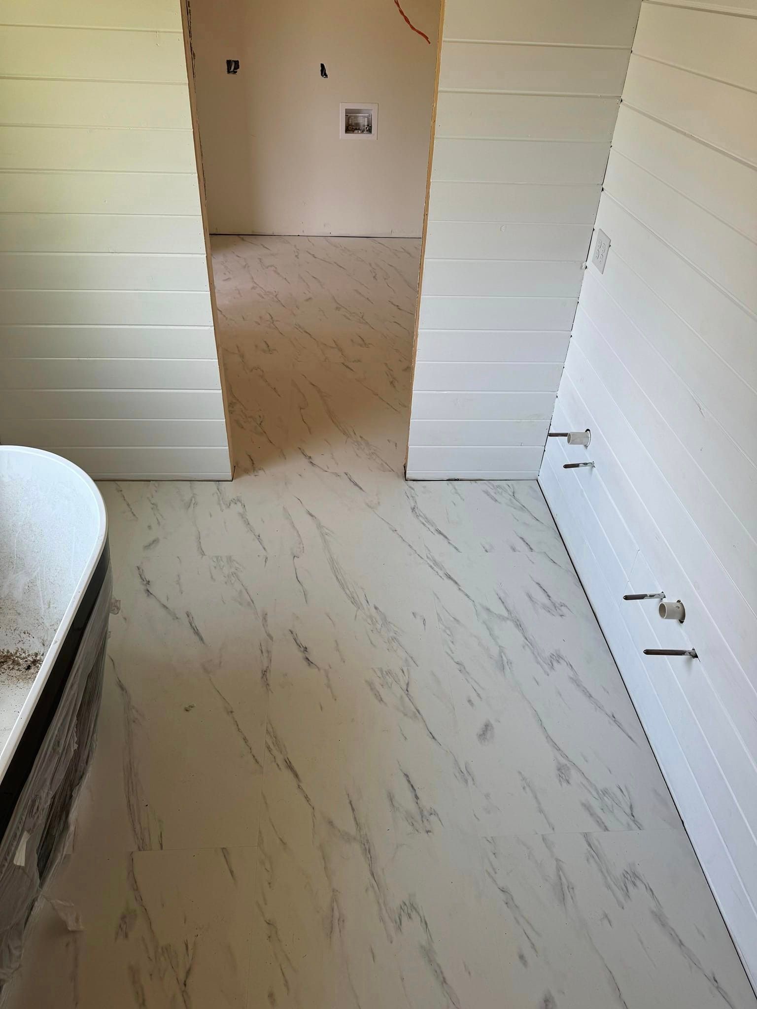 A bathroom with a bathtub and a marble floor.