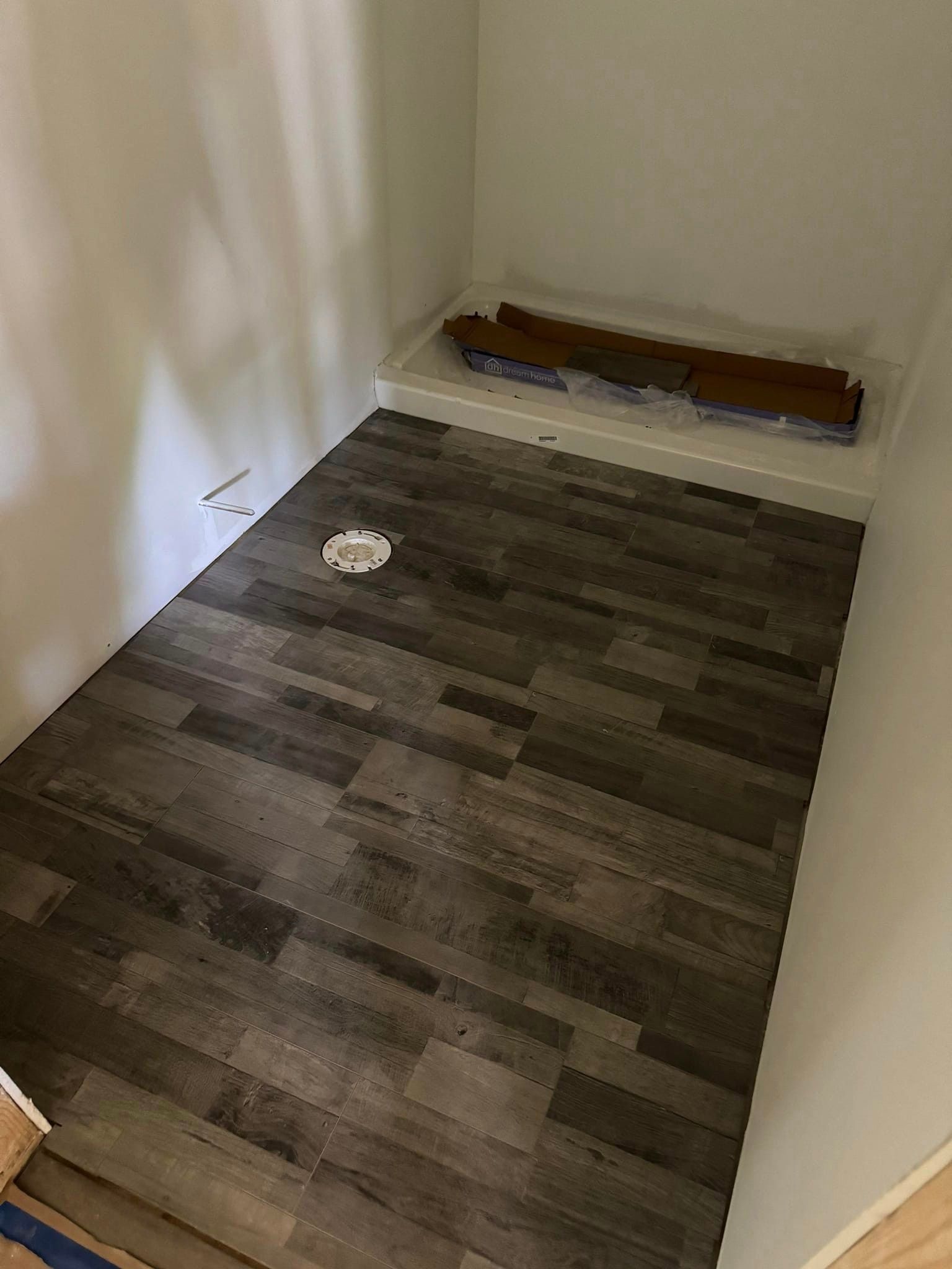 A bathroom with a wooden floor and a shower stall.