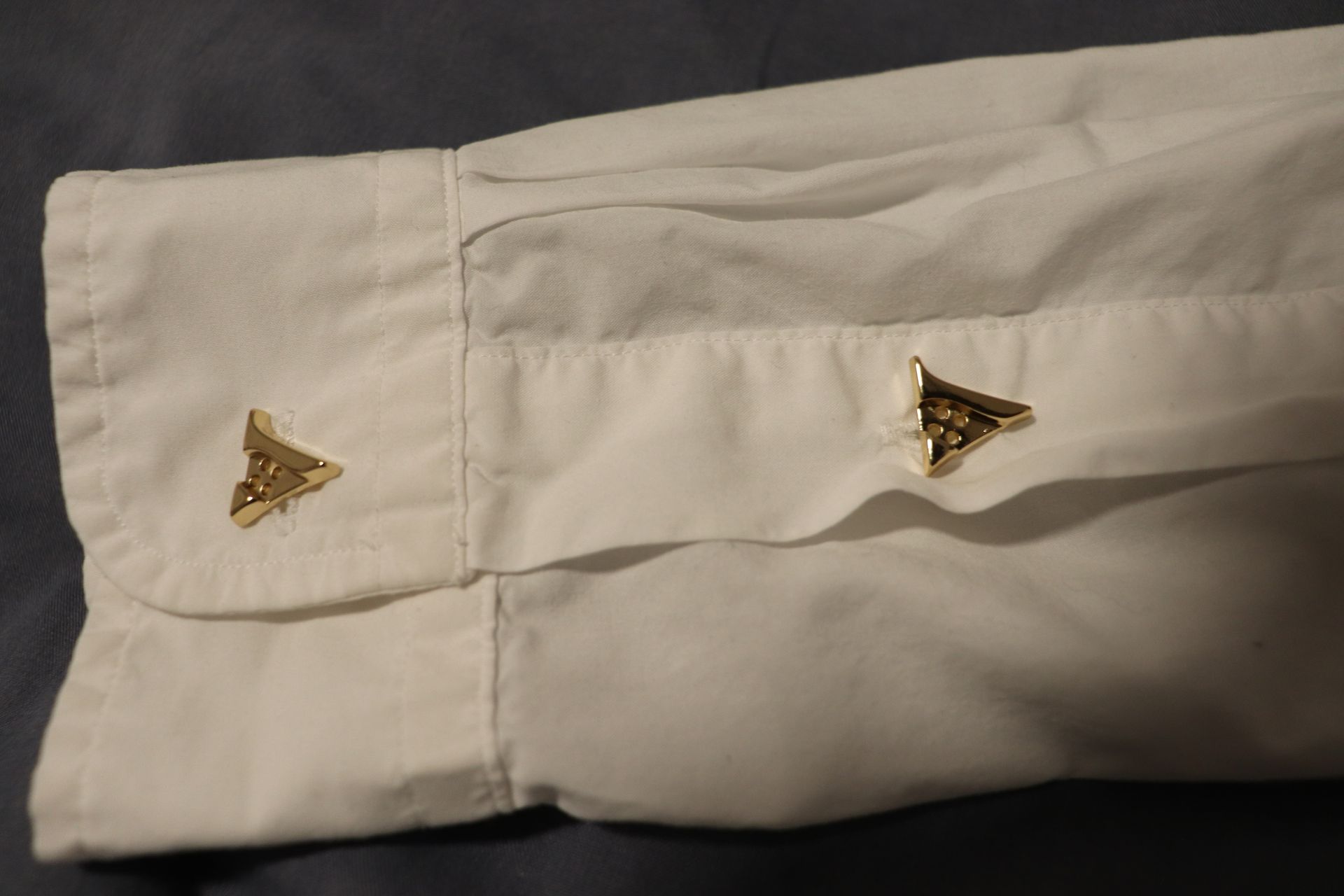 Close-up of a polished gold button on a luxury hoodie, engraved with the Vena Vici emblem
