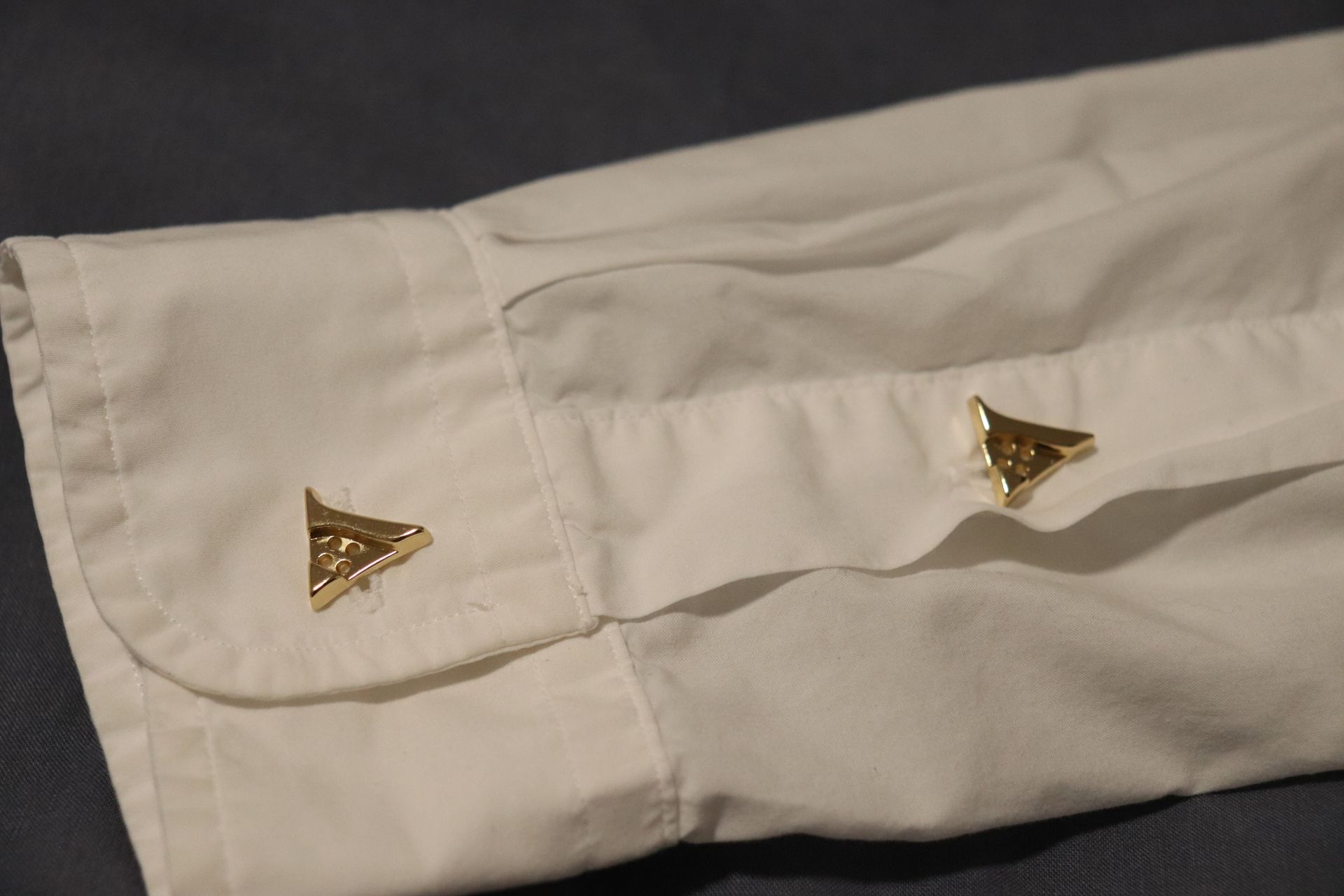 Close-up of a polished gold button on a luxury hoodie, engraved with the Vena Vici emblem
