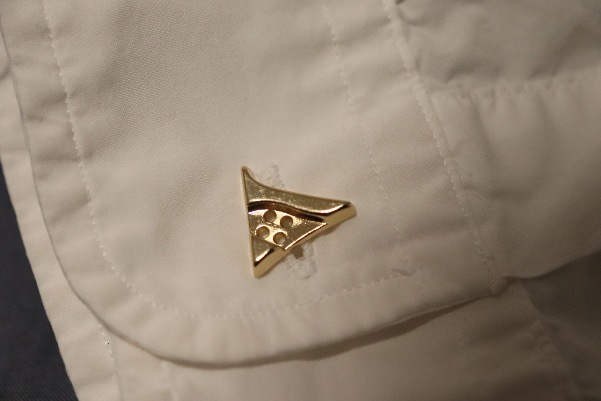 Close-up of a polished gold button on a luxury hoodie, engraved with the Vena Vici emblem
