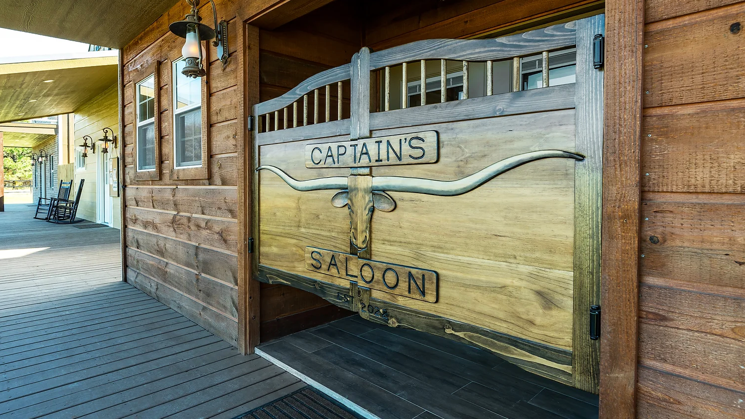 A wooden door with a longhorn on it is open to a saloon.