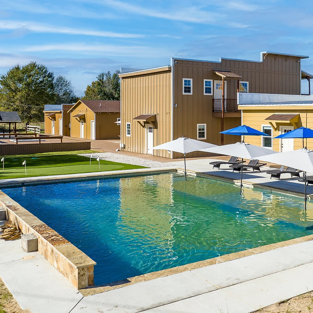 A large swimming pool surrounded by chairs and umbrellas