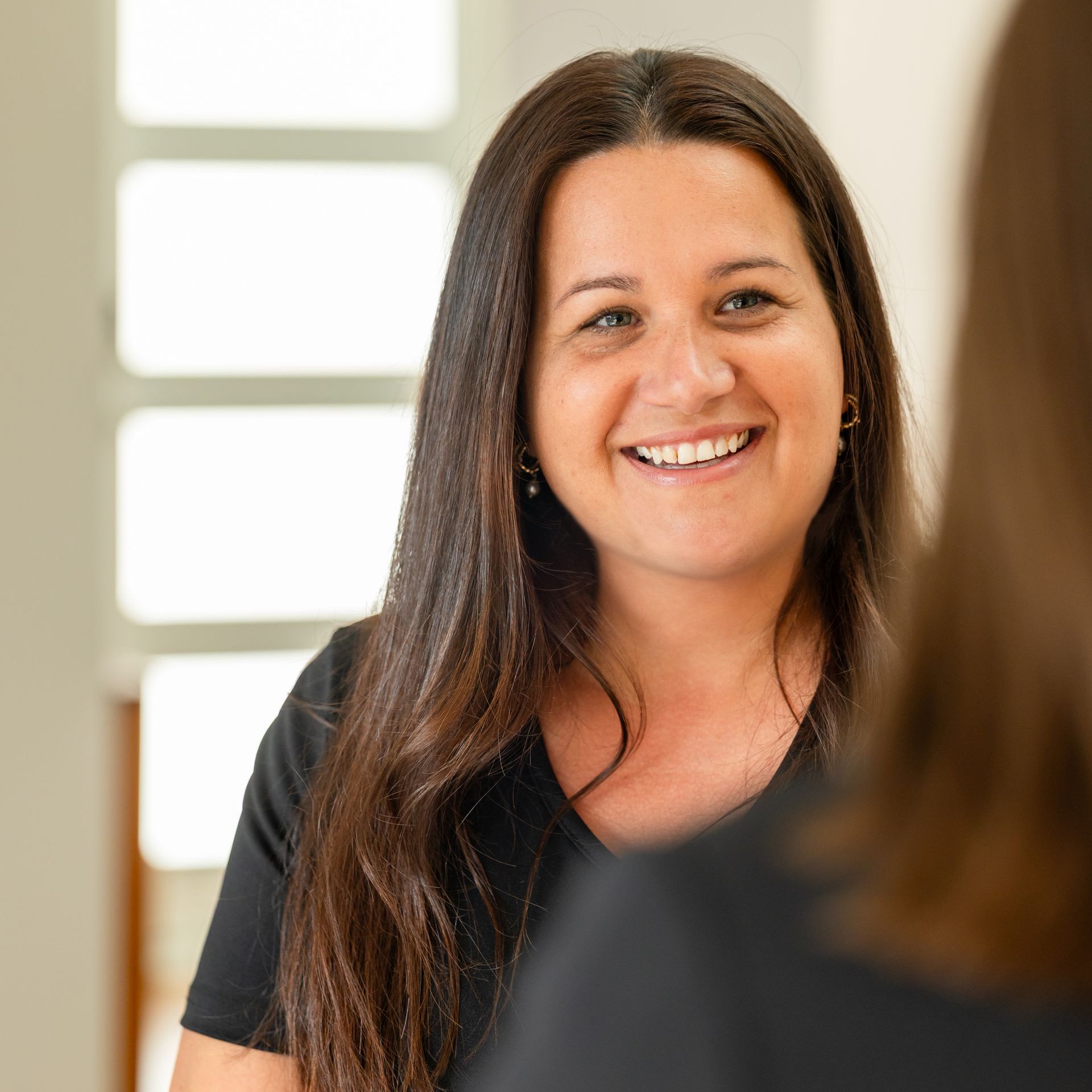 A woman is smiling while looking at herself in the mirror.