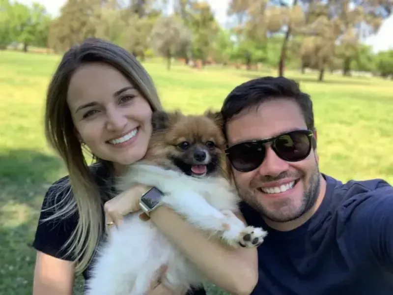 Couple smiling with small dog outdoors in park