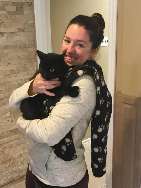 Woman smiling, holding a black cat