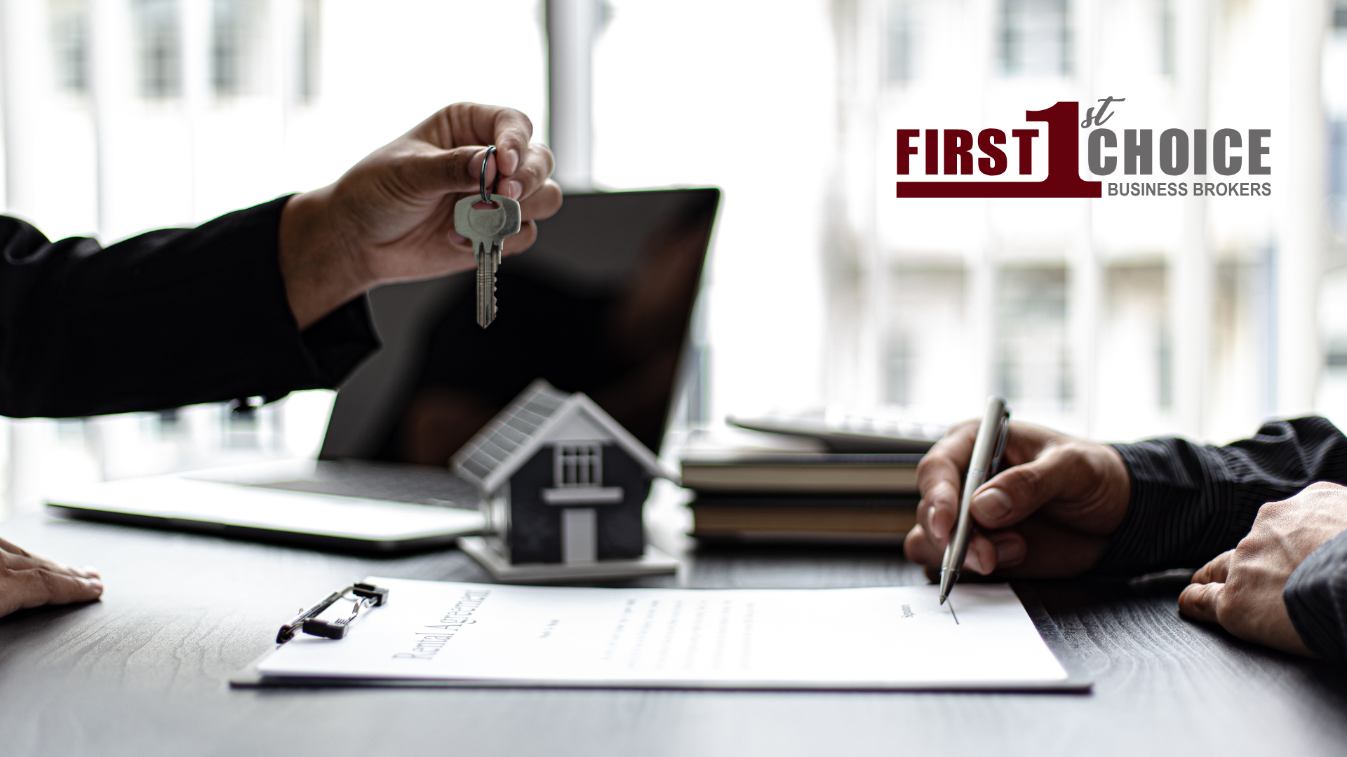 A man is giving a house key to another man while signing a document.