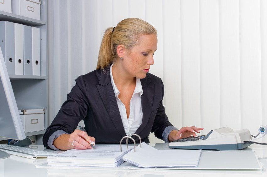 A female accountant working in an office with files and calculator