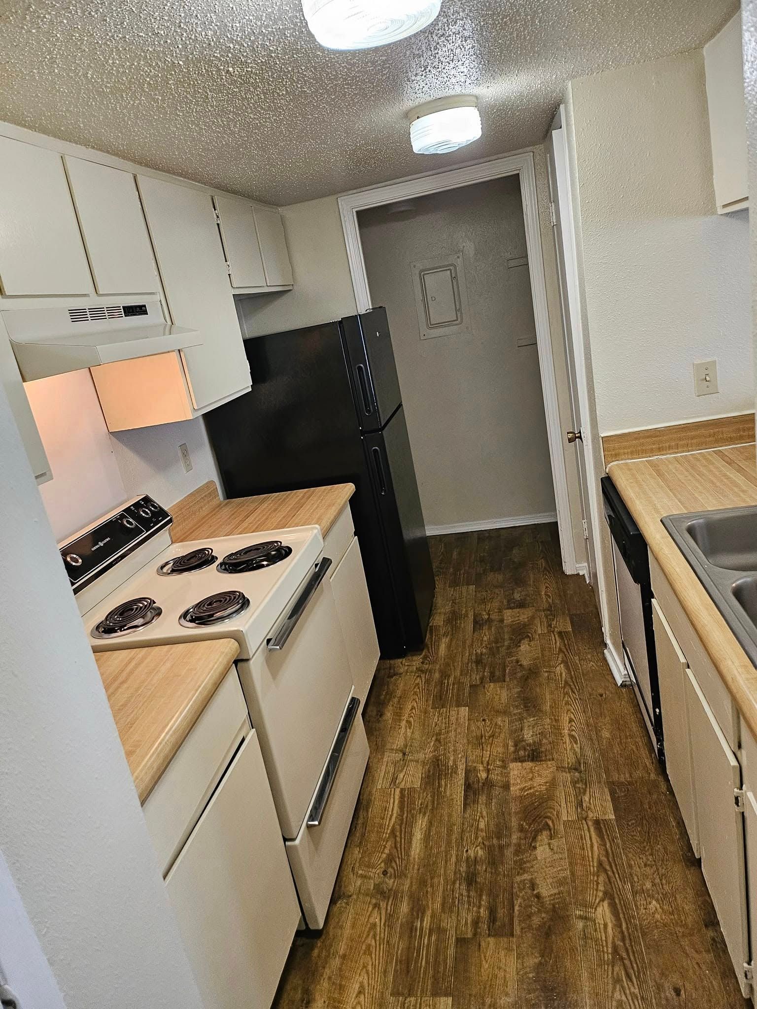 A kitchen with a stove , refrigerator , sink and cabinets.