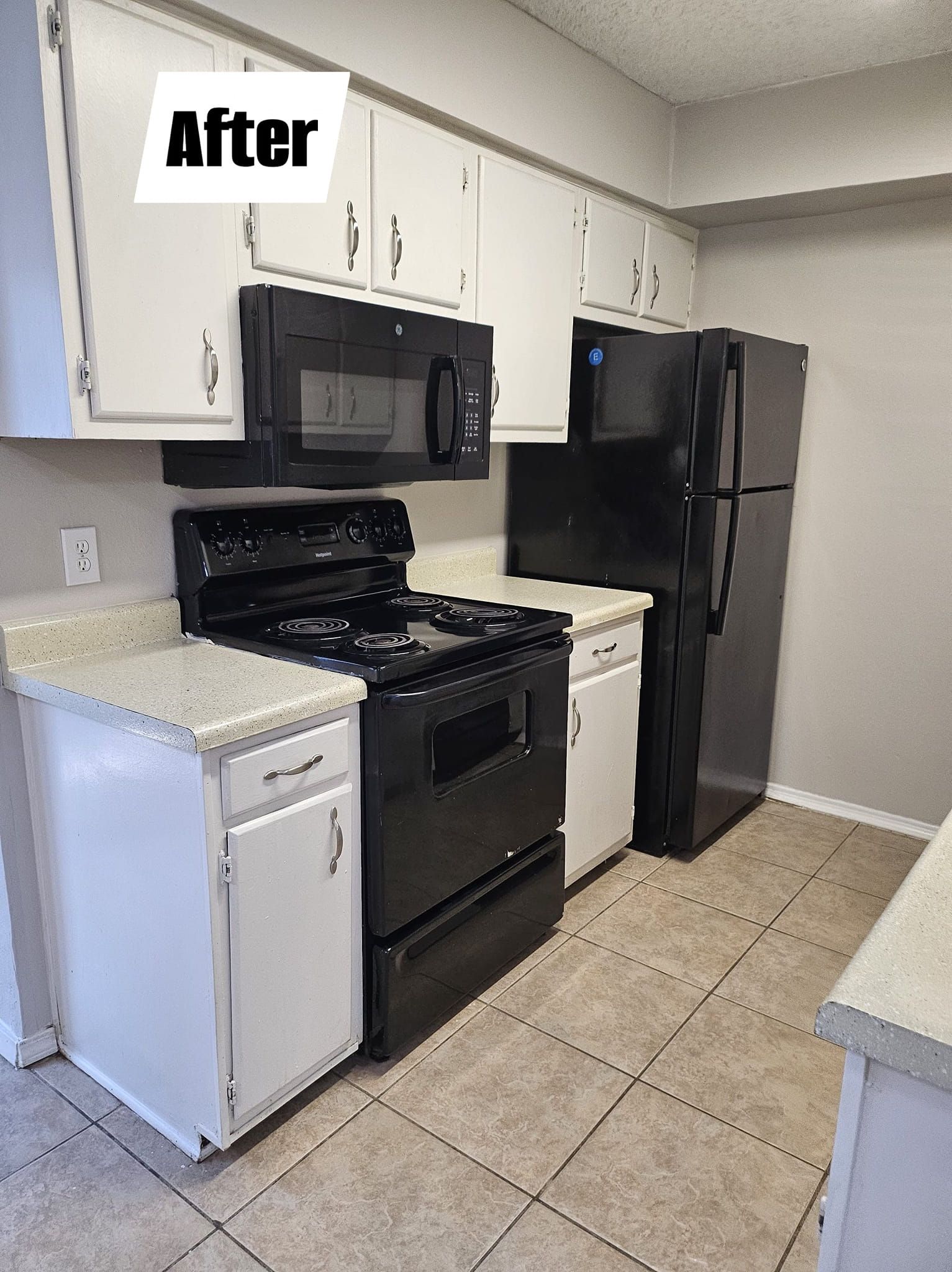 A kitchen with white cabinets , black appliances , and a black refrigerator.
