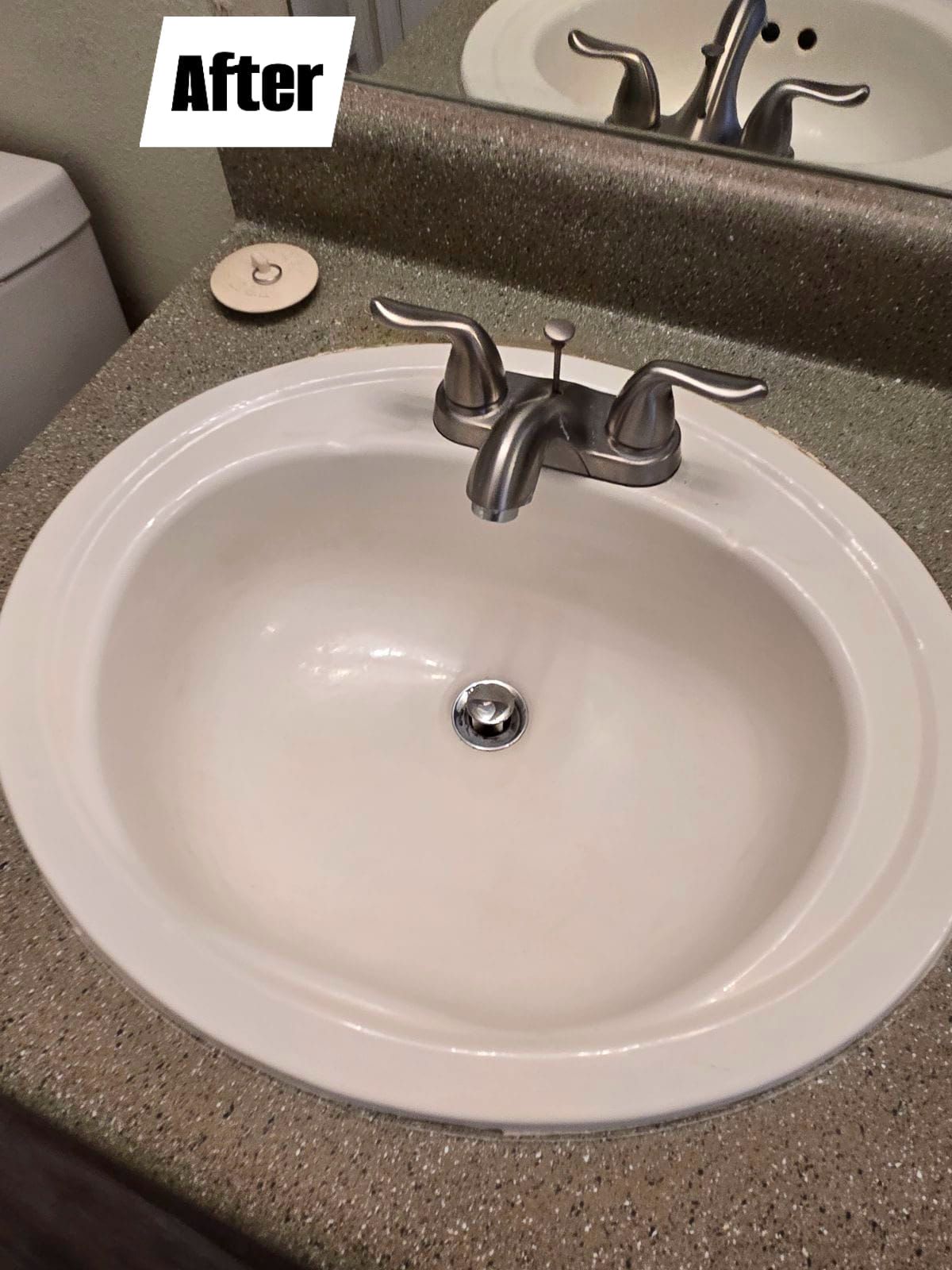 A bathroom sink is sitting on a counter next to a toilet.
