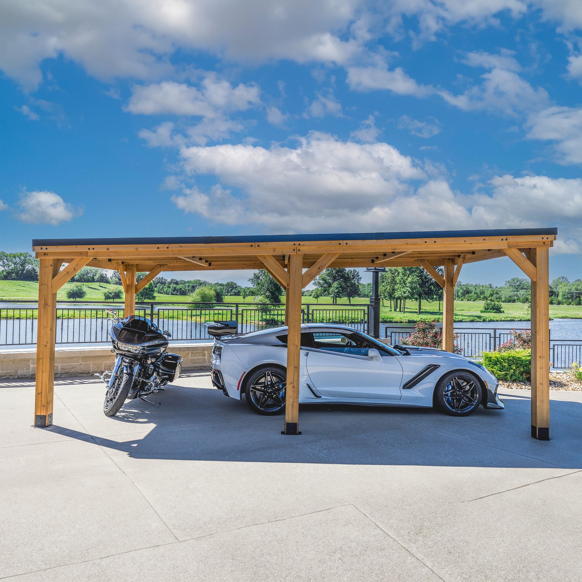 Wooden carport with a white sports car and motorcycle parked beneath it. Blue sky background.