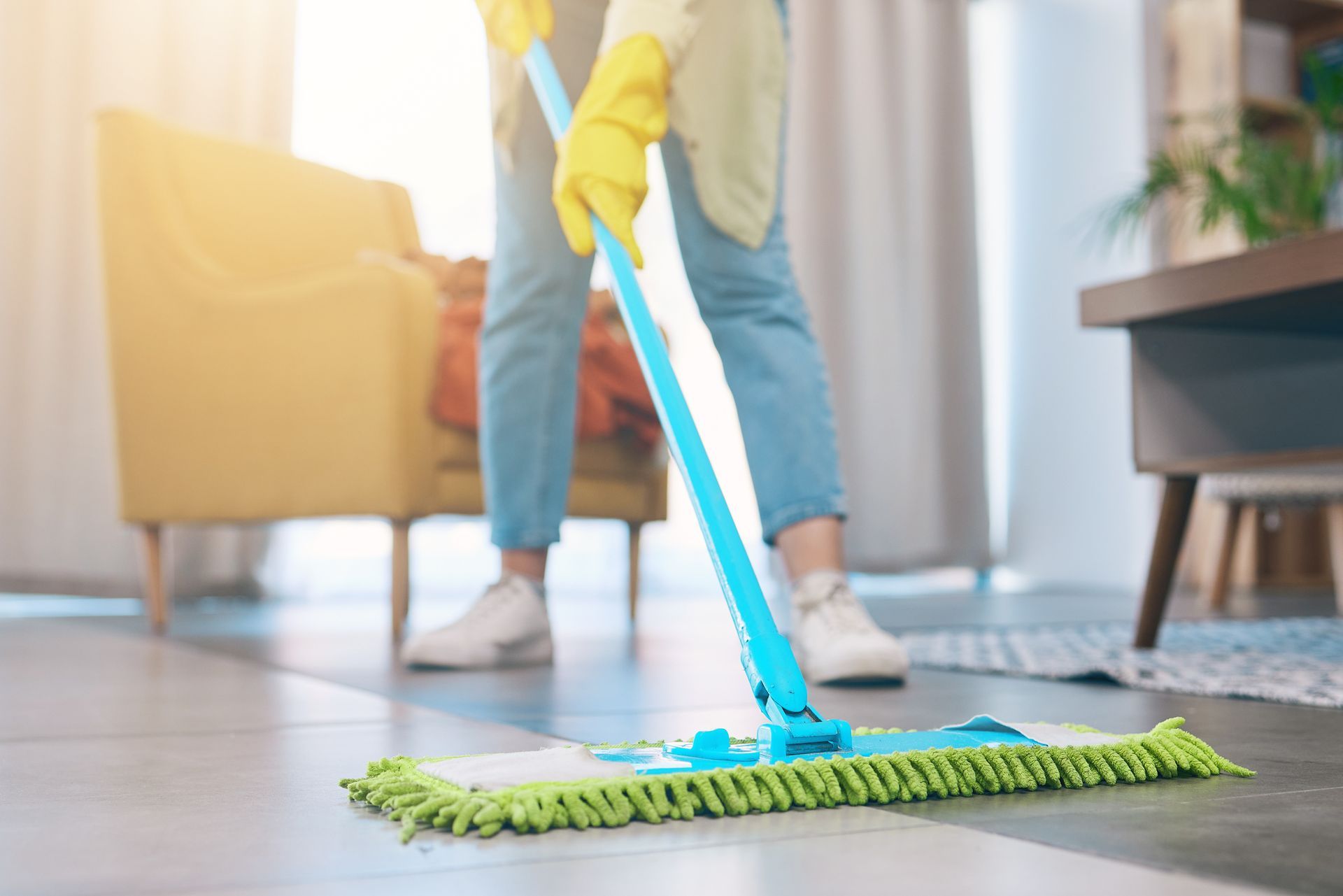 A woman is cleaning the floor with a mop in a living room.