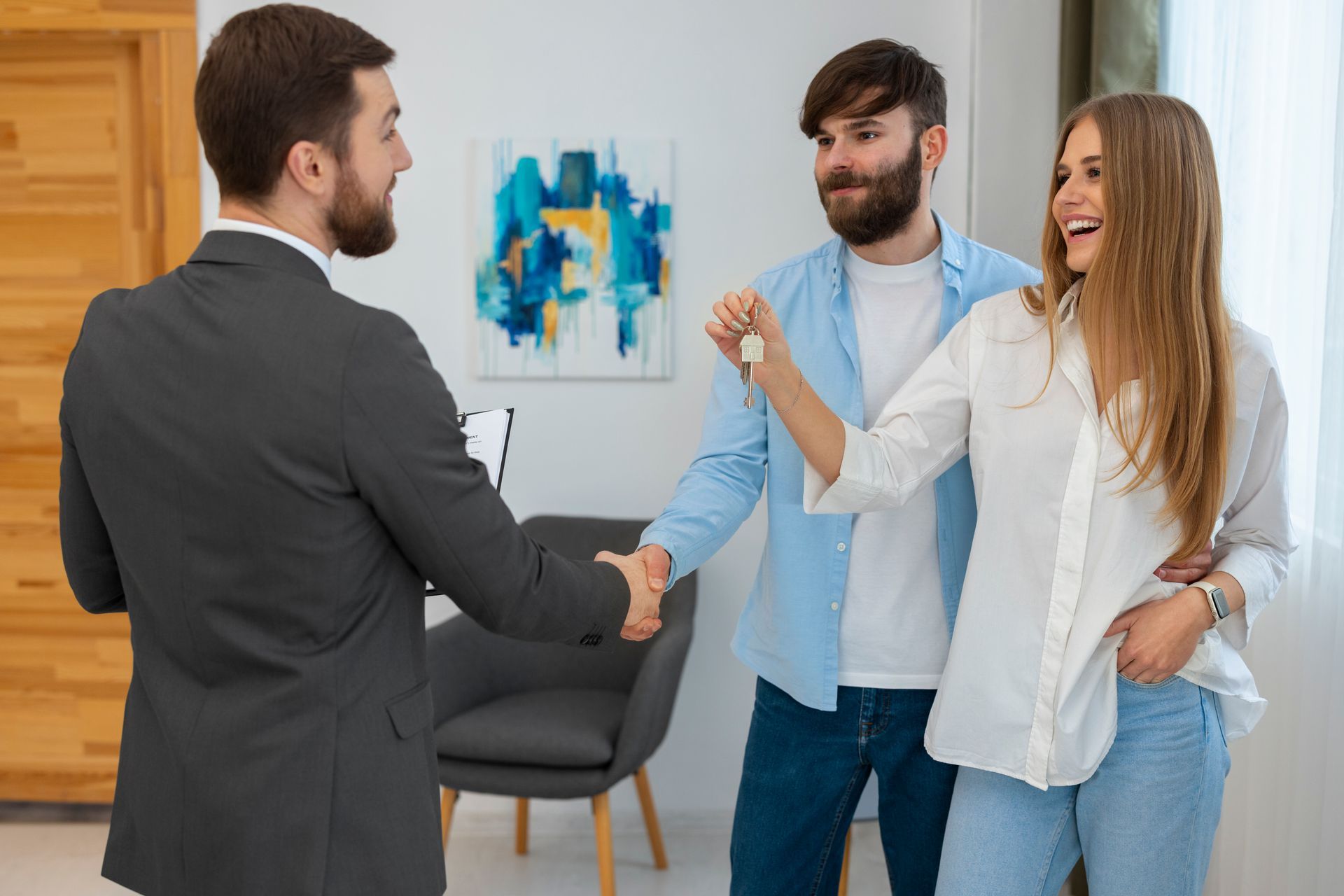 A man and woman are shaking hands with a real estate agent in a living room.