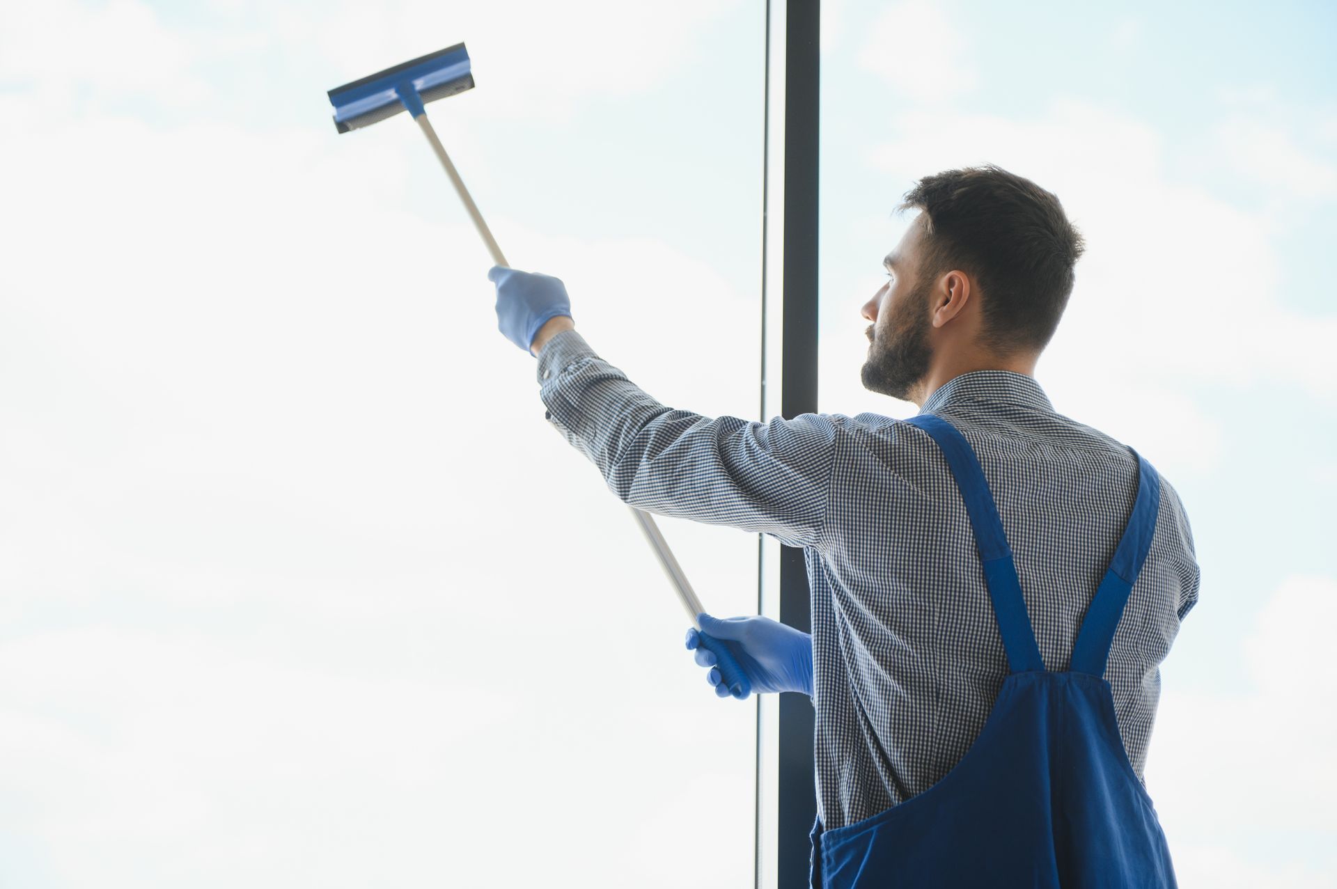 A man is cleaning a window with a mop.