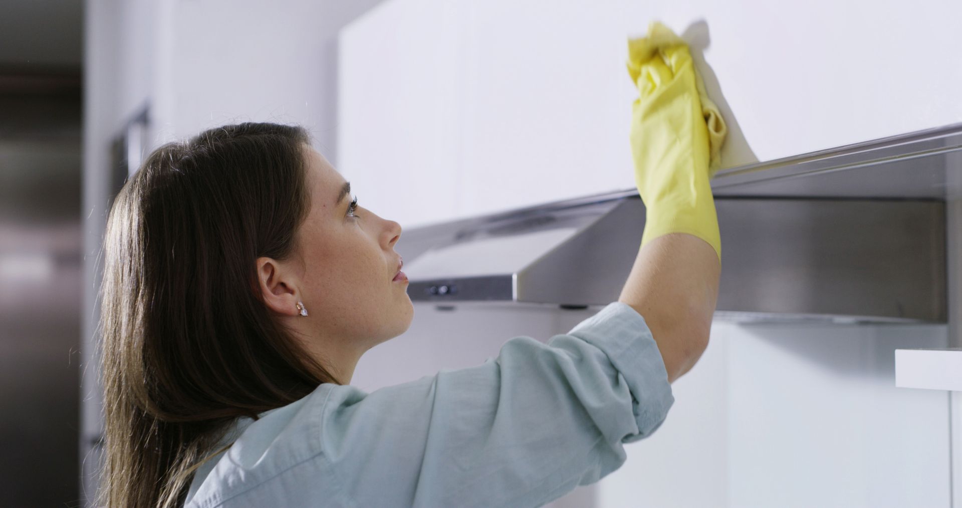 a woman wiping the kitchen cabinet area