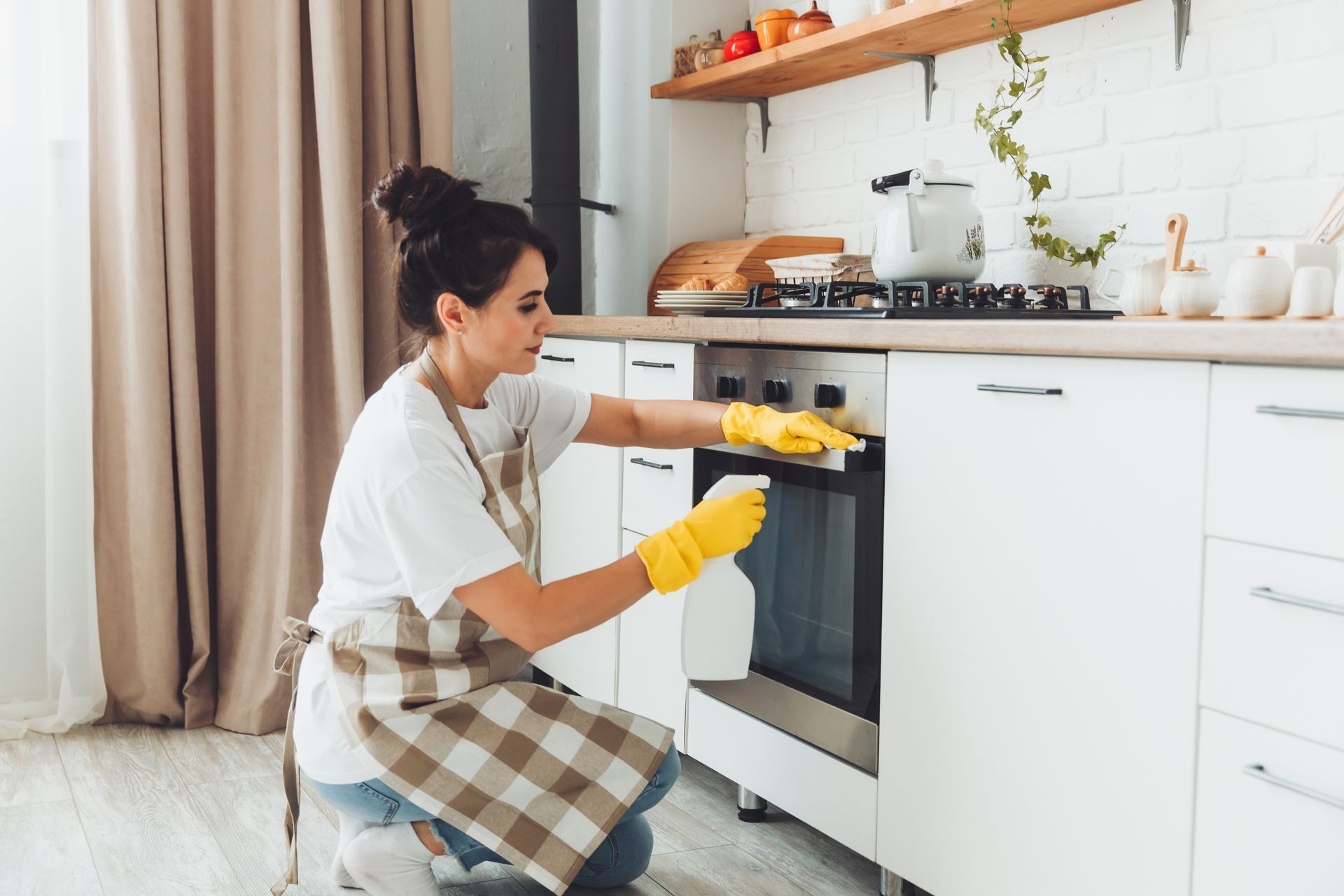 A woman is cleaning the oven in a kitchen.