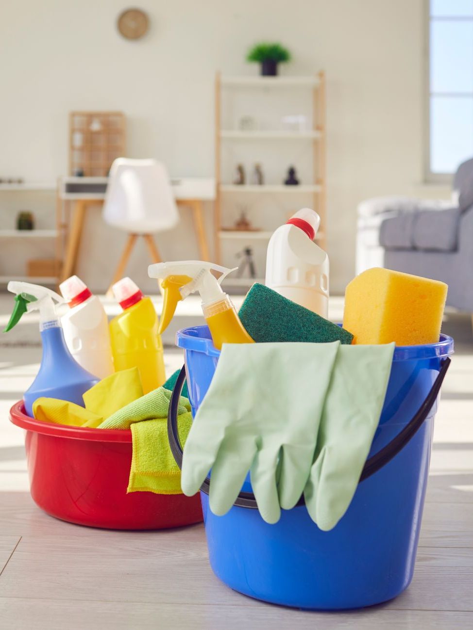 Two buckets filled with cleaning supplies in a living room.