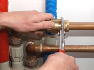 Plumber tightening a bolt on a copper pipe