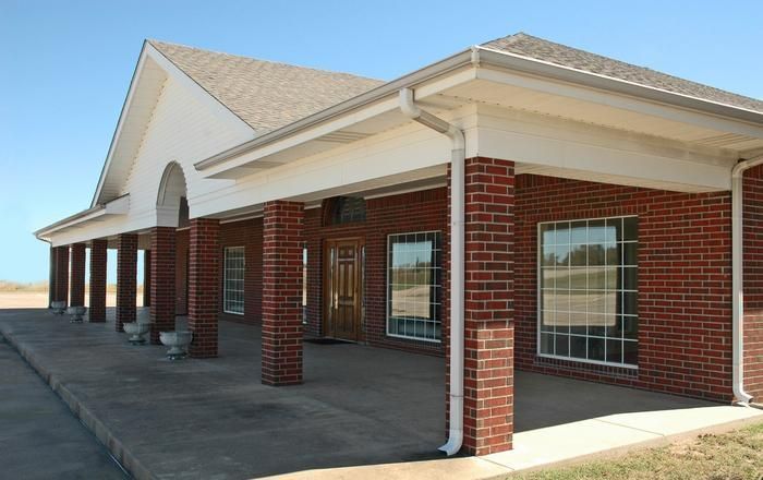 Red brick building with white trim, porch, and a brown wooden door.