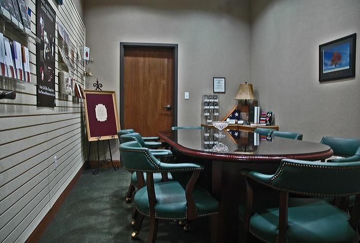A conference room with a large oval table, green chairs, and a wooden door.